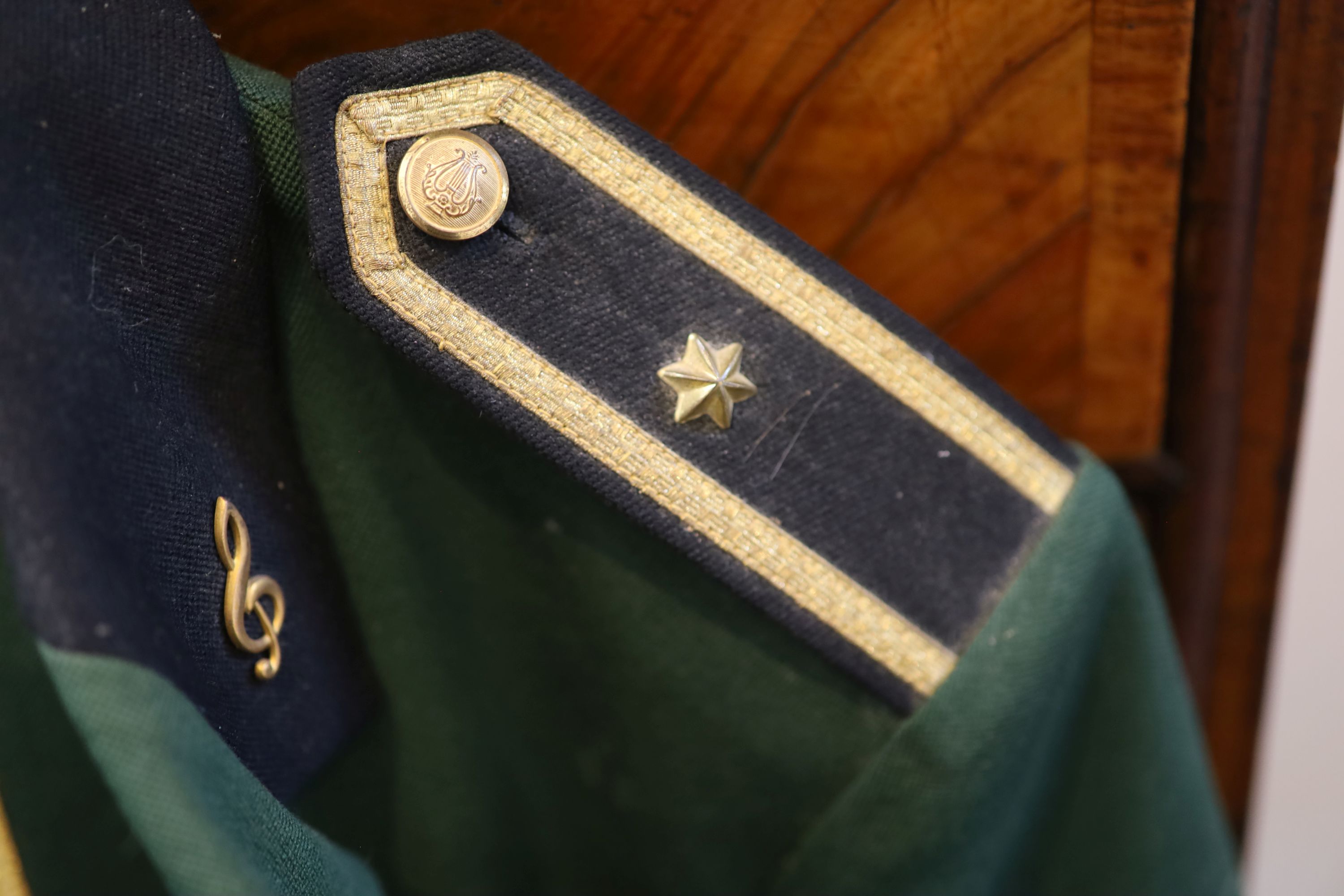 A grey top hat, a black Trilby hat and a bottle green and black uniform